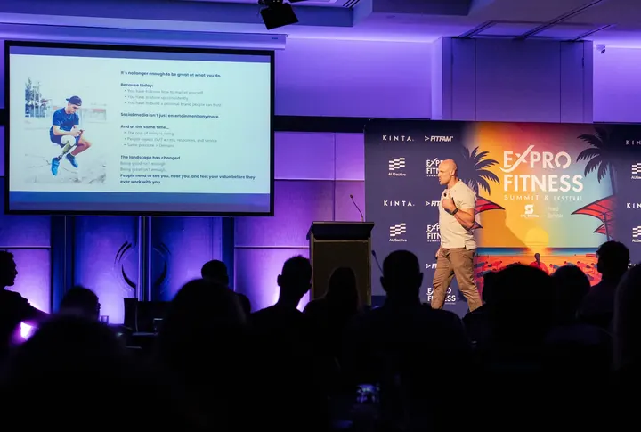 Martin speaking on stage at a professional fitness conference
